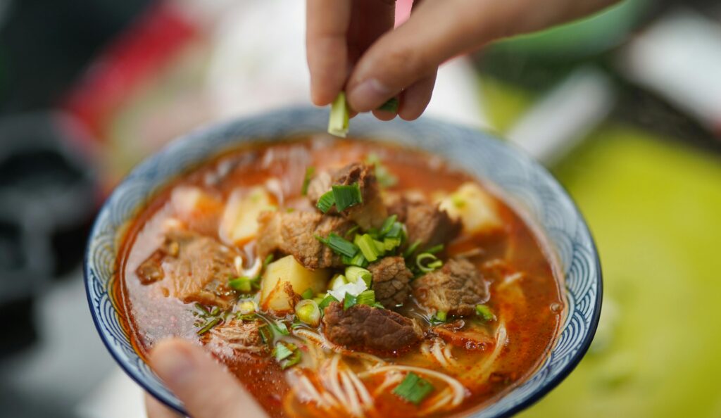 Delicious spicy beef noodle soup garnished with fresh green onions, perfect for homemade meals.